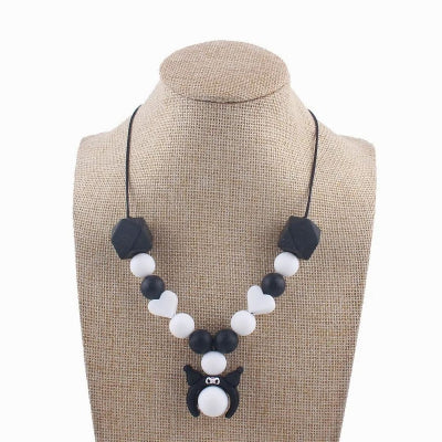Collier d’allaitement noir et blanc avec pendentif chaton et perles en forme de cœur, parfait pour les mamans minimalistes et modernes.