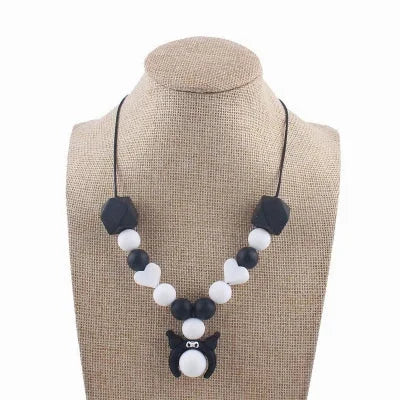 Collier d’allaitement noir et blanc avec pendentif chaton et perles en forme de cœur, parfait pour les mamans minimalistes et modernes.