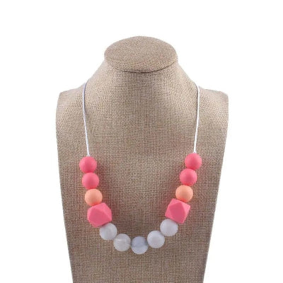 Collier d’allaitement rose et corail avec grosses perles à mâchouiller, pour apaiser bébé et renforcer le lien parent-enfant.