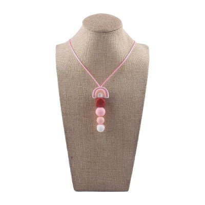 Collier d’allaitement en silicone rose poudré présenté sur buste, accessoire sensoriel conçu pour apaiser les gencives et favoriser l’éveil de bébé en toute sécurité.

