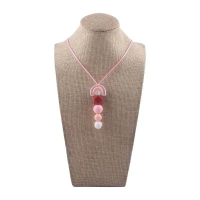 Collier d’allaitement en silicone rose poudré présenté sur buste, accessoire sensoriel conçu pour apaiser les gencives et favoriser l’éveil de bébé en toute sécurité.

