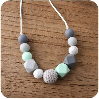 Collier d’allaitement en silicone gris et menthe avec perle crochetée, idéal pour les poussées dentaires et la stimulation sensorielle de bébé pendant l’allaitement.

