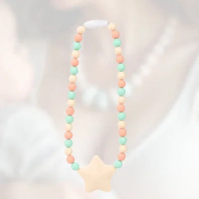 Collier d’allaitement pastel en silicone alimentaire avec étoile crème, idéal pour stimuler la motricité fine de bébé pendant l’allaitement ou le portage.

