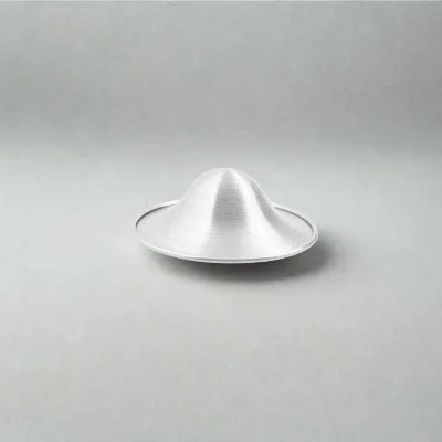 Présentation d’une coupelle d’allaitement en argent sur fond neutre mettant en valeur son design concave et respirant