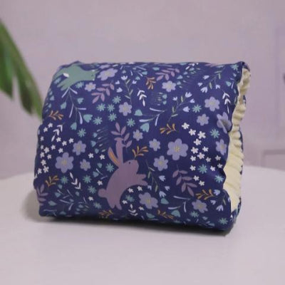 Coussin d’allaitement pour bras violet avec motifs lapins et fleurs, conçu pour offrir confort et maintien pendant l’allaitement de bébé.