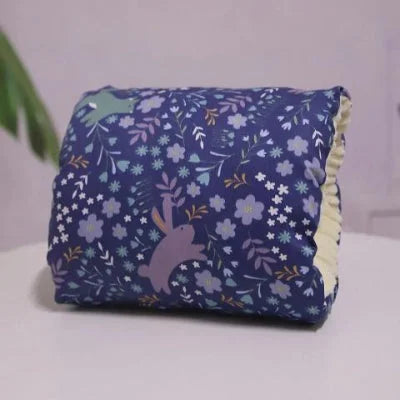 Coussin d’allaitement pour bras violet avec motifs lapins et fleurs, conçu pour offrir confort et maintien pendant l’allaitement de bébé.