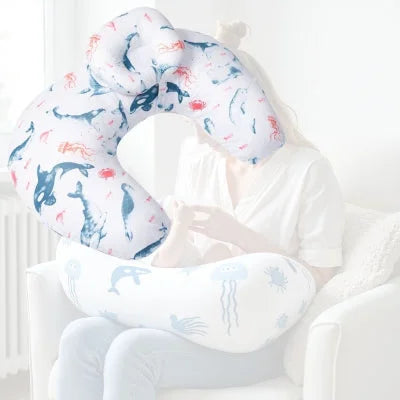 Maman nourrissant son bébé avec un coussin d’allaitement imprimé animaux marins, conçu pour réduire les tensions au niveau des bras et faciliter la succion de bébé.