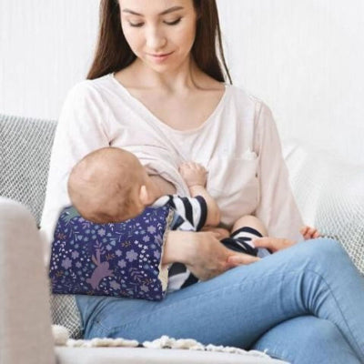 Maman allaitant avec coussin d’allaitement ergonomique sur l’avant-bras, motif floral violet, pour soulager la tension au bras et maintenir bébé dans une position confortable.