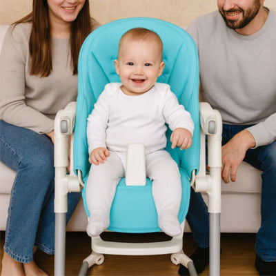 Bébé assis confortablement sur un coussin chaise haute bébé turquoise avec harnais de sécurité, housse de chaise haute bébé confort adaptée aux repas en famille.