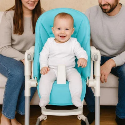 Bébé assis confortablement sur un coussin chaise haute bébé turquoise avec harnais de sécurité, housse de chaise haute bébé confort adaptée aux repas en famille.