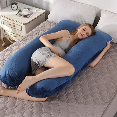 Femme enceinte allongée confortablement sur le coussin de grossesse CalinForm™ bleu foncé, position latérale idéale pour soulager les lombaires.