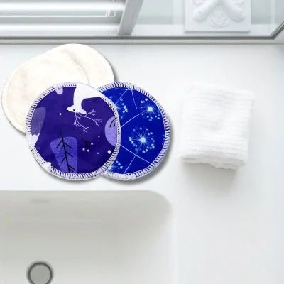 Coussinets d'allaitement CosmicTouch™ en gros plan, posés sur un comptoir de salle de bain minimaliste, alliant style et fonctionnalité.