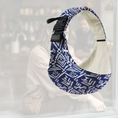 Echarpe de portage bébé bleue à motifs ethniques utilisée par une maman en intérieur – portage stylé et confortable.