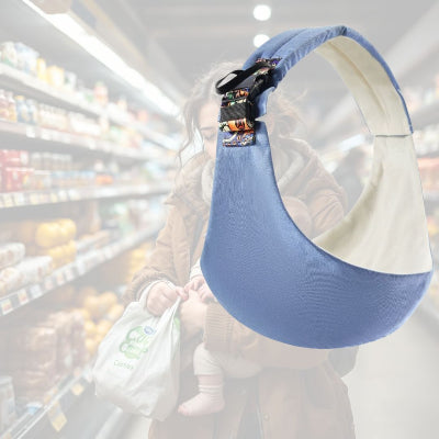 Maman avec bébé en écharpe de portage bleu clair dans un supermarché – portage physiologique en sortie.