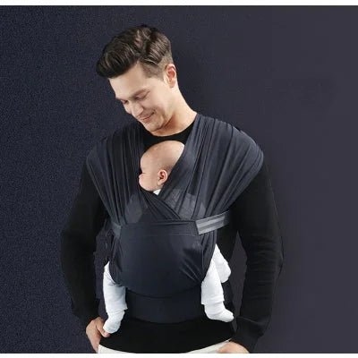 Papa portant son bébé dans une écharpe de portage noire physiologique, position ventrale sécurisée.