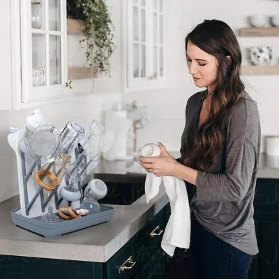 Jeune maman utilisant un égouttoir biberon compact sur son plan de travail pour organiser les accessoires de son bébé.