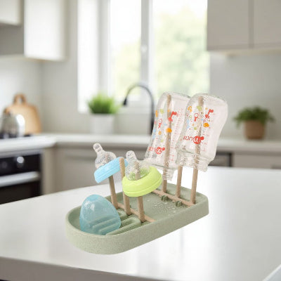 Egouttoir biberon vert en situation dans une cuisine moderne avec lumière naturelle, mettant en valeur son design compact et pratique.