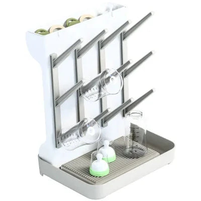 Support de séchage pour biberons et accessoires avec tétines, capuchons et bouteilles sur un égouttoir vertical pratique.