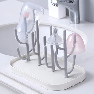 Egouttoir biberon BiberZen™ posé près d’un lavabo, utilisé pour sécher un biberon, une tétine et un capuchon, assurant un séchage hygiénique rapide.