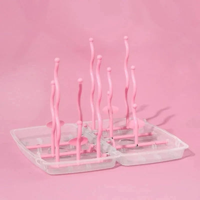 Égouttoir biberon pliable rose poudré avec tiges courbées, conçu pour maximiser l’espace de séchage tout en ajoutant une touche douce et moderne.