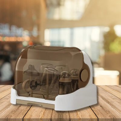 Égouttoir biberon PureDrop™ posé sur une table en bois dans un environnement lumineux, montrant la protection complète offerte par le couvercle fumé contre les poussières et les microbes.