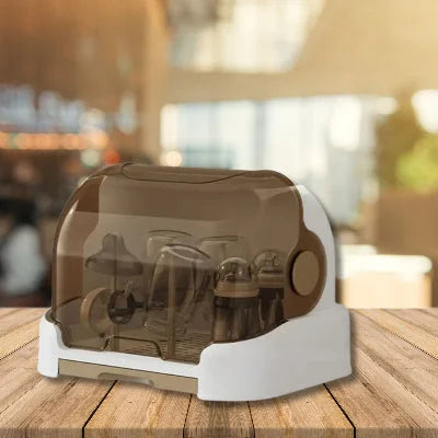 Égouttoir biberon PureDrop™ posé sur une table en bois dans un environnement lumineux, montrant la protection complète offerte par le couvercle fumé contre les poussières et les microbes.