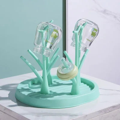 Égouttoir biberon couleur turquoise avec structure en branches, compact et pratique pour sécher les accessoires d’allaitement dans une petite cuisine.

