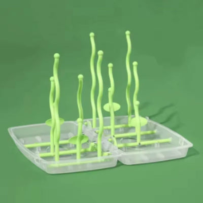  Égouttoir biberon pliable vert avec bras ondulés sur socle transparent, parfait pour les accessoires de puériculture lors de déplacements ou à la maison.