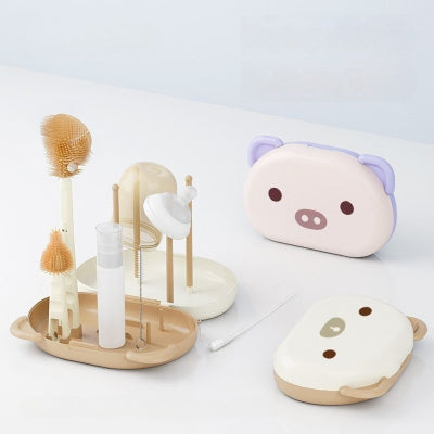 Goupillon biberon complet avec égouttoir, flacon savon, brosse paille et tétine, présenté avec deux boîtes de rangement rigides en forme d’animal.