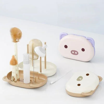 Goupillon biberon complet avec égouttoir, flacon savon, brosse paille et tétine, présenté avec deux boîtes de rangement rigides en forme d’animal.