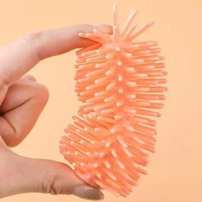 Détail de la matière souple du goupillon biberon montrant sa flexibilité entre deux doigts, garantissant un lavage doux et efficace des biberons.