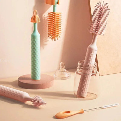  Goupillon biberon en version rose et vert menthe posé à côté d’un biberon, illustrant les deux coloris disponibles et les embouts adaptés à chaque usage.
