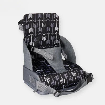 Gros plan sur un rehausseur chaise pliable motif flèches gris et noir, harnais ajustable et sangles de fixation pour chaise standard.
