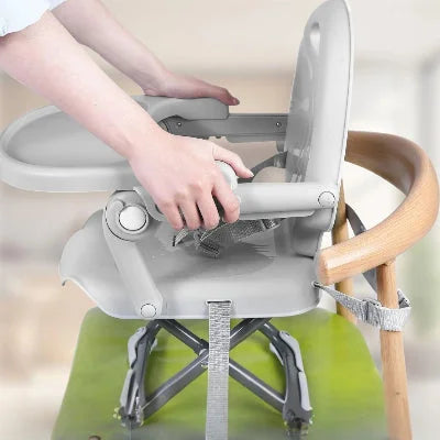 Installation d’un réhausseur de chaise bébé gris avec ceintures de sécurité réglables fixées sur une chaise adulte, siège de table bébé stable et pratique pour les repas.
