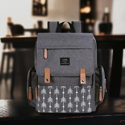 Sac à Dos à Langer ÉlégancePlus™ - Gris Nordic avec motifs flèches blanches. Un sac tendance, fonctionnel et résistant, idéal pour les mamans et papas actifs.