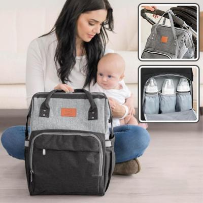 Une maman moderne assise dans un salon avec son bébé, utilisant le sac à langer SerenityPack™ pour une organisation optimale et un moment de complicité.