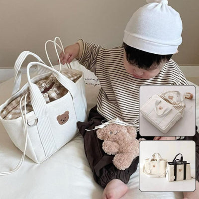 Sac à langer crème élégant avec tissu intérieur vichy, accompagné d’un bébé jouant, idéal pour ranger les essentiels des tout-petits tout en restant stylé.