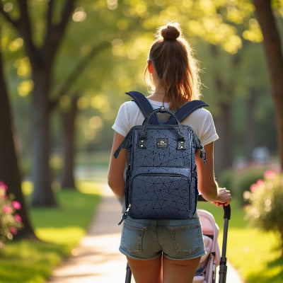 Sac à dos à langer bleu profond porté par une mère dans un parc ensoleillé, équipé de poches spacieuses et idéal pour transporter les affaires de bébé.