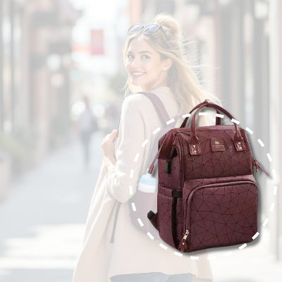 Sac à dos à langer bordeaux chic avec compartiments multiples, porté par une mère élégante lors d'une promenade en ville, démontrant style et utilité.