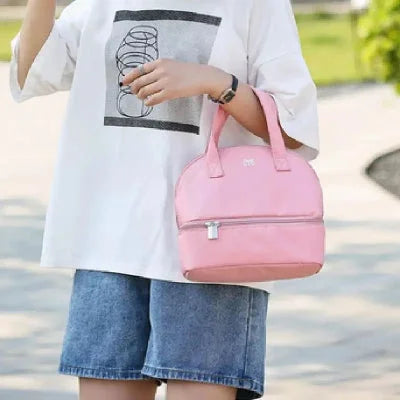 Sac isotherme bébé rose porté à la main par une jeune maman lors d'une promenade, pratique pour les sorties quotidiennes avec bébé.