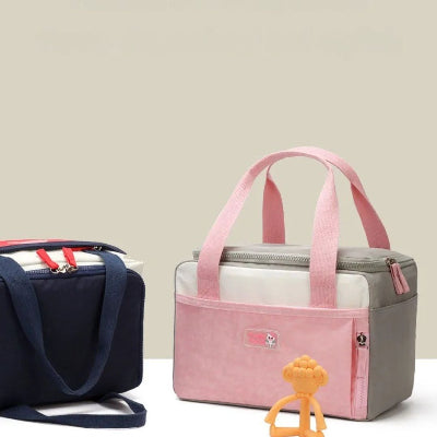 sac isotherme Bebe rose et rouge présenté sur fond neutre avec jouet bébé, parfait pour sorties, crèche ou repas nomade