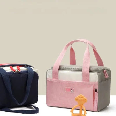sac isotherme Bebe rose et rouge présenté sur fond neutre avec jouet bébé, parfait pour sorties, crèche ou repas nomade