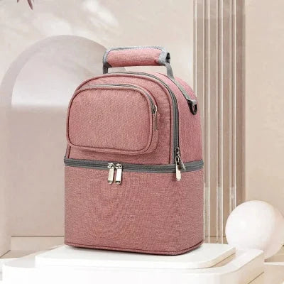  Sac isotherme Bebe rose BibiCool™ avec double compartiment thermique et poignée renforcée, posé dans un décor élégant.