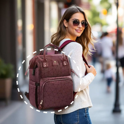 Jeune femme élégante portant le sac à dos à langer Bordeaux Chic dans une rue animée, idéal pour les sorties en ville grâce à ses poches multifonctions et son port USB.