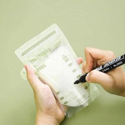 Personne inscrivant la date sur un sachet conservation lait maternel avec un marqueur fourni, facilitant le suivi de la fraîcheur du lait.