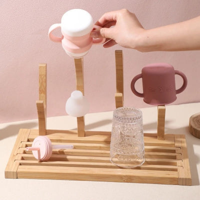Sèche biberon DryNest™ avec biberon et tasses installés, démonstration d’usage pour jeunes parents, idéal pour une organisation efficace de la cuisine.