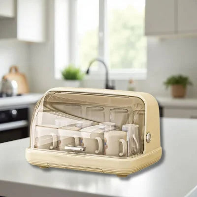 Sèche biberon BibStand™ couleur beige sur îlot central de cuisine, mise en valeur du design élégant et fonctionnel pour un gain de place optimal.

