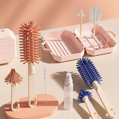 Kit complet du sèche biberon DryMimi™ avec version rose et bleue, support de séchage, brosses souples, flacon doseur et boîte pliable.
