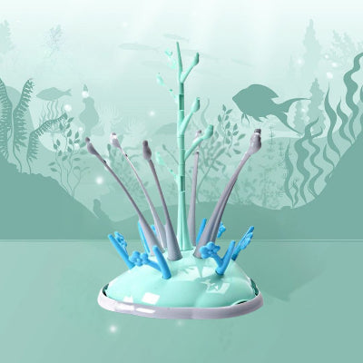 Sèche biberon en plastique vert menthe avec embouts gris et crochets bleus, dans un décor inspiré du monde marin, parfait pour la cuisine moderne.

