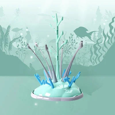 Sèche biberon en plastique vert menthe avec embouts gris et crochets bleus, dans un décor inspiré du monde marin, parfait pour la cuisine moderne.


